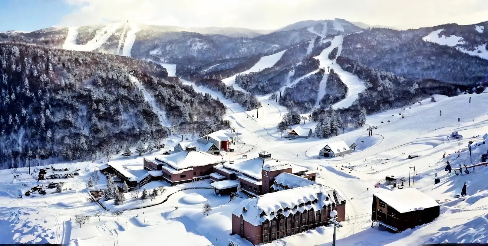 Japan ski resort with skiers on snow covered mountain winter landscape — Karvaan Tours