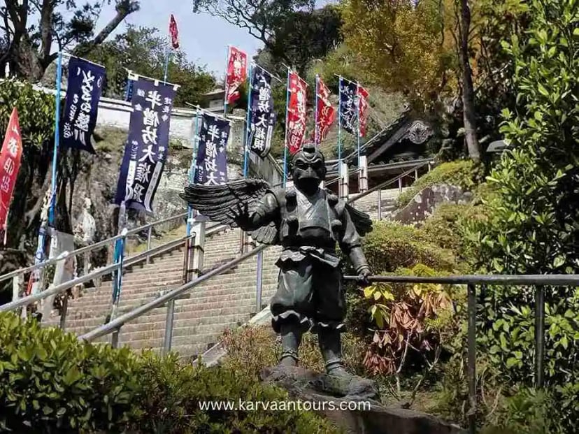 Stone staircase with colorful banners and guardian statue at Hasedera Temple in Kamakura