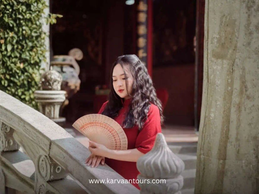 Woman in red kimono holding a folding fan near temple structure at Hasedera Temple in Kamakura