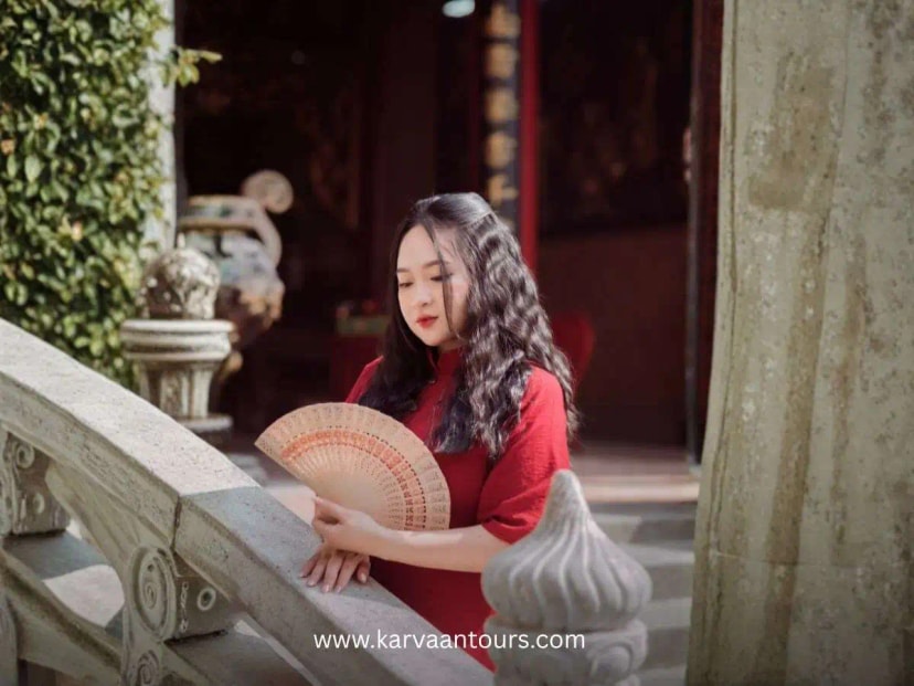Woman in red kimono holding a folding fan near temple structure at Hasedera Temple in Kamakura