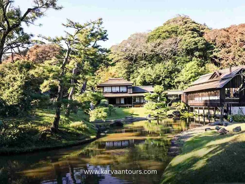 Traditional Japanese house beside a calm pond with trees in Sankeien Garden Yokohama
