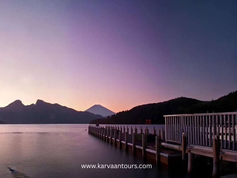 Sunset view of Lake Ashi with calm water, pier, and Mount Fuji visible in the background in Hakone Japan