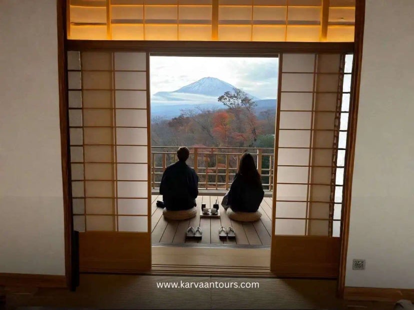 Woman in kimono performing a traditional Japanese tea ceremony inside a tatami room with tea utensils