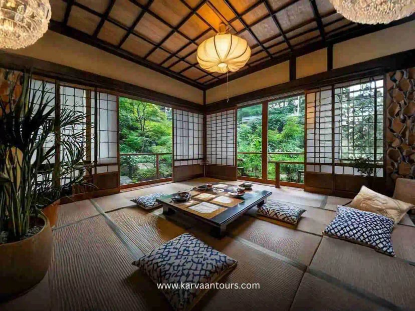 Two people sitting on tatami mats in a traditional Japanese room looking out at Mount Fuji through open shoji doors