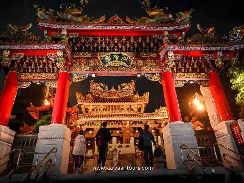 Illuminated Yokohama Chinatown entrance gate at night with visitors walking toward the temple