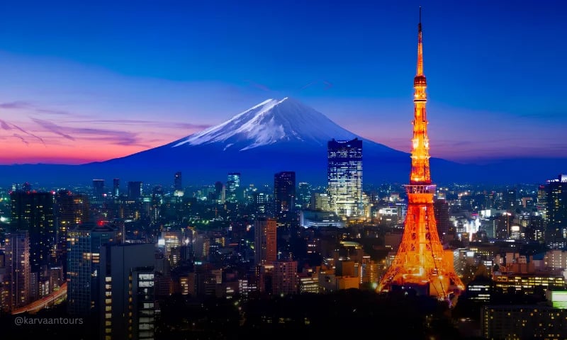 Tokyo Tower illuminated at dusk with Mount Fuji visible in the distance