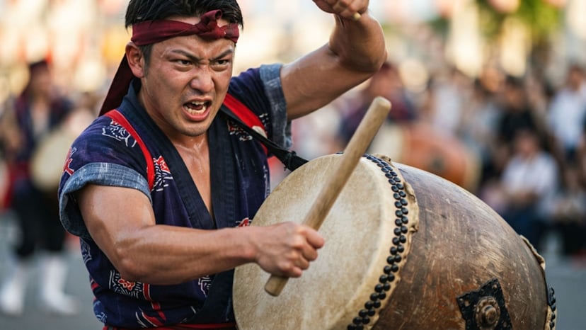 A close-up of an Okinawan drummer in traditional costume playing a large drum.