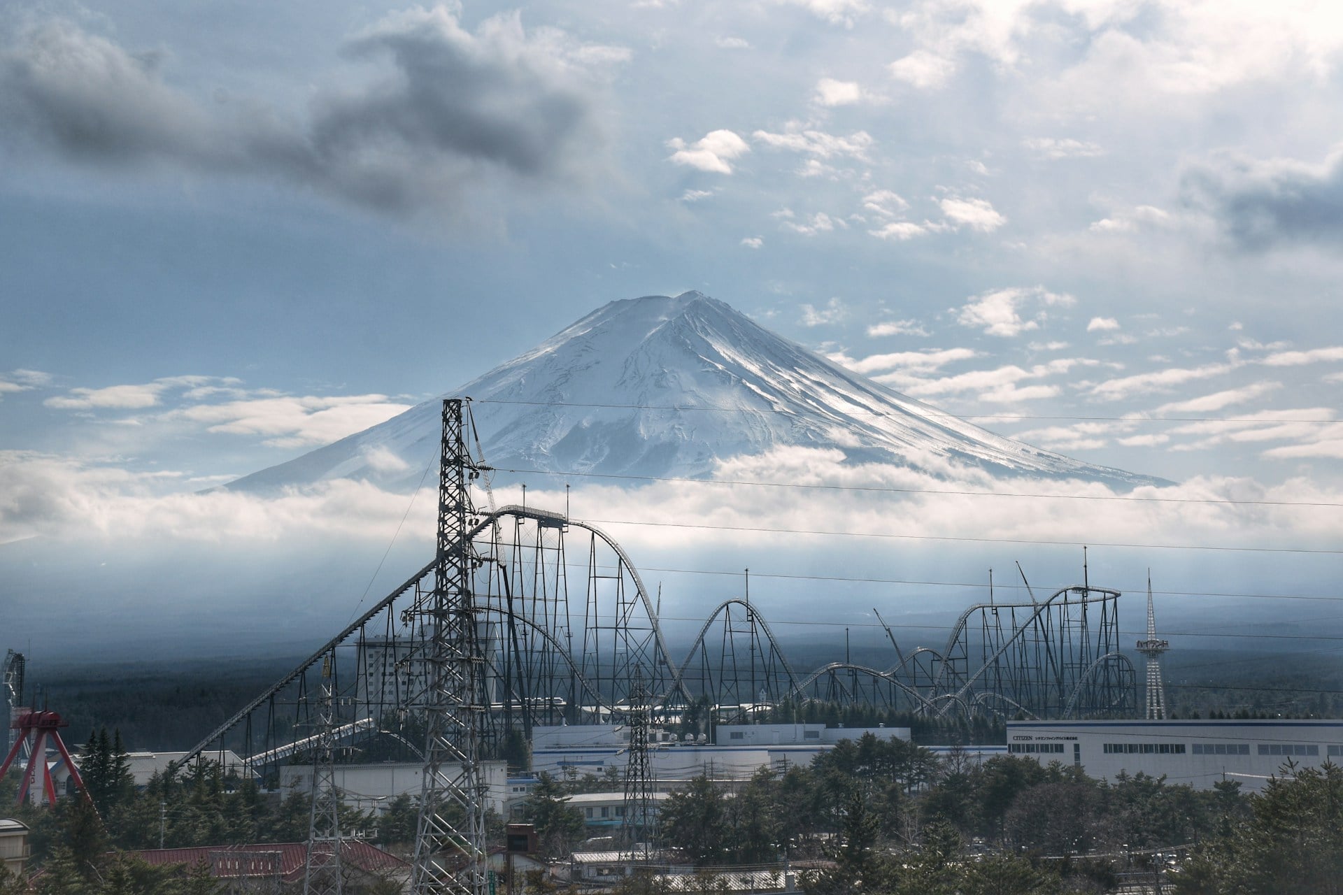 Fuji-Q Highland Private Tour by Car with Hotel Pickup Mount Fuji rising above clouds behind a roller coaster at Fuji-Q Highland