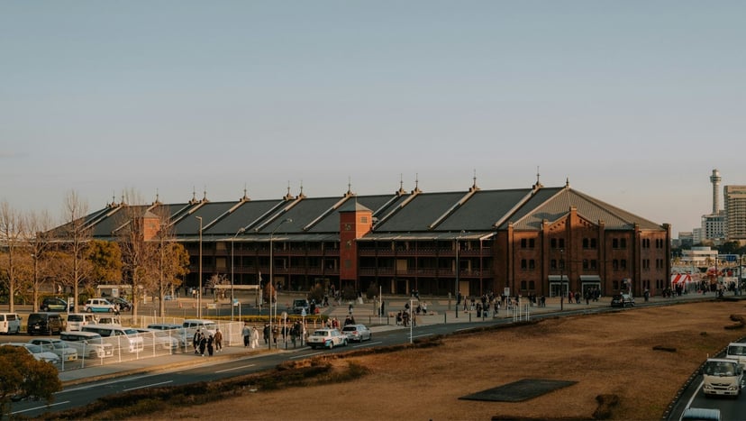 Wide exterior shot of Yokohama Red Brick Warehouse with historic red brick architecture and surrounding plaza on a clear day.