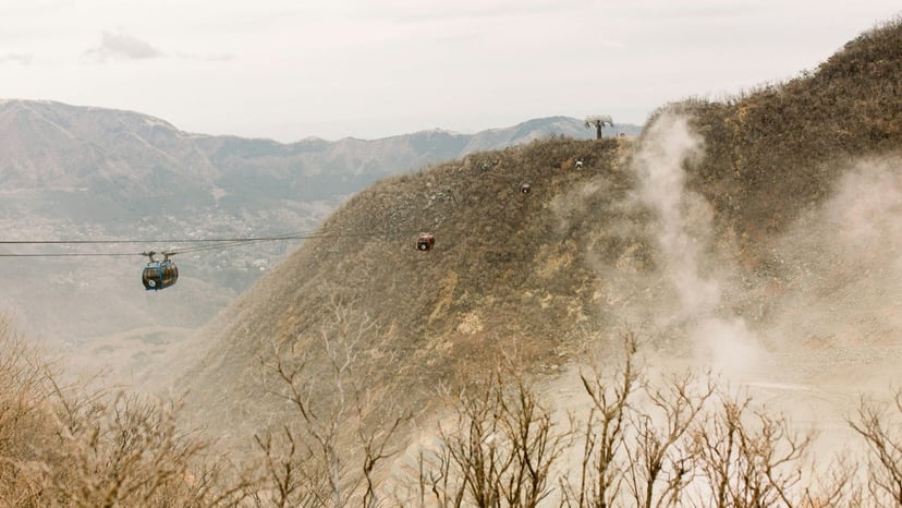 Aerial gondola cabin travelling over the rugged, steaming slopes of Owakudani volcanic valley.